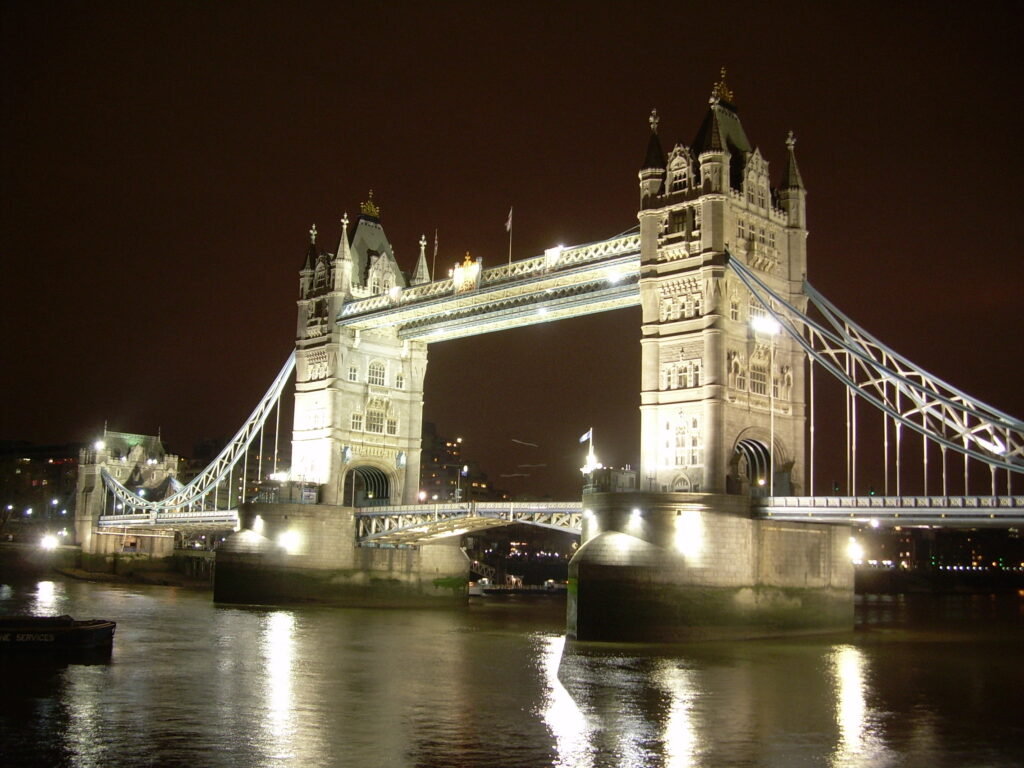 Tower Bridge, a 2-level bridge with prominent towers, lit up at night in London