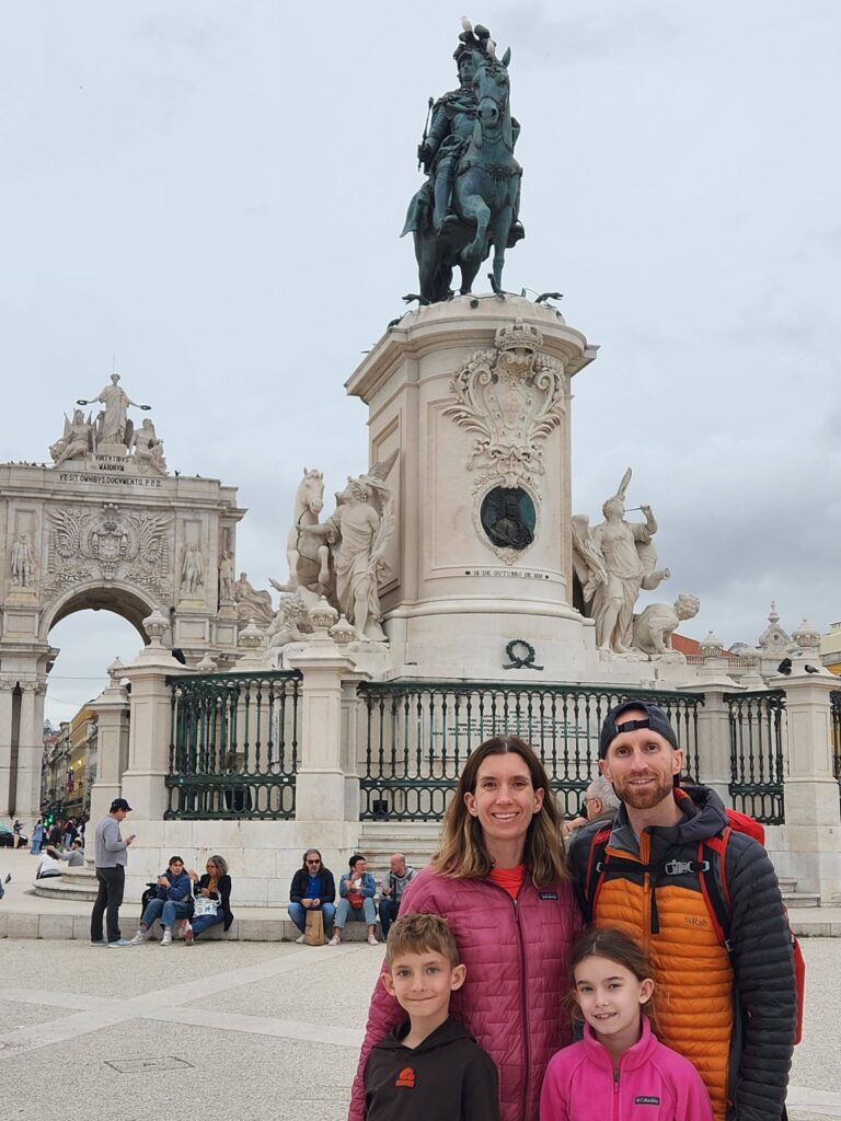 A family posing in front of a statue in Praca do Comercio