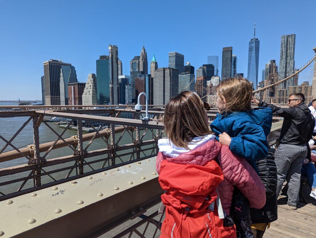 A woman holding a small child looking at the Manhattan skyline in New York City
