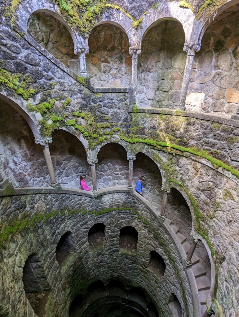 Two children descending a stone spiral staircase in Sintra, Portugal