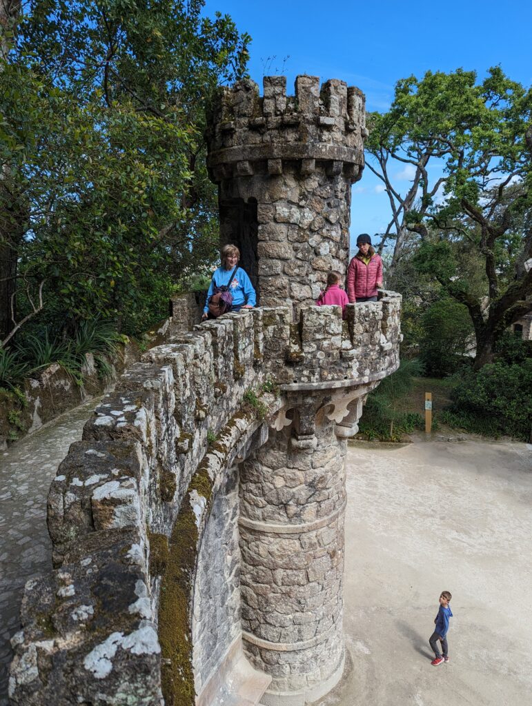 A boy on the ground looking up at several people on a stone tower in Sintra, Portugal