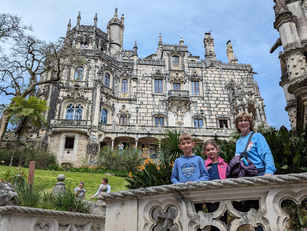 A woman and 2 children standing in front of Quinta da Regaleira in Sintra, Portugal