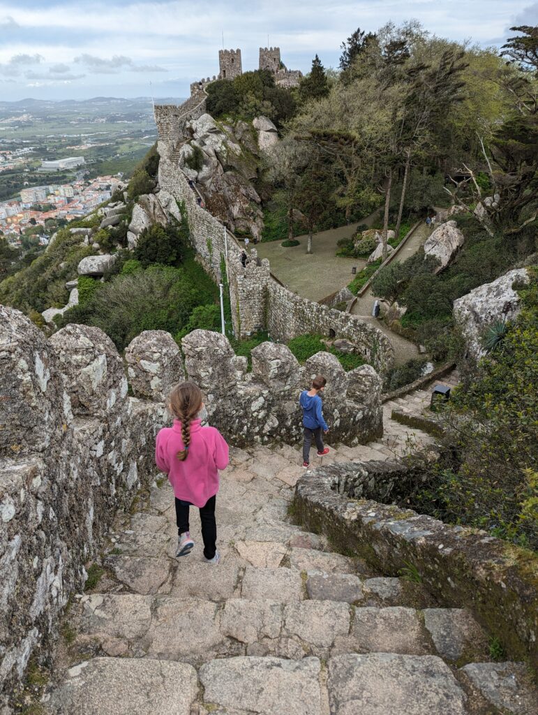 Two kids descending a stone staircase along castle walls in Sintra, Portugal
