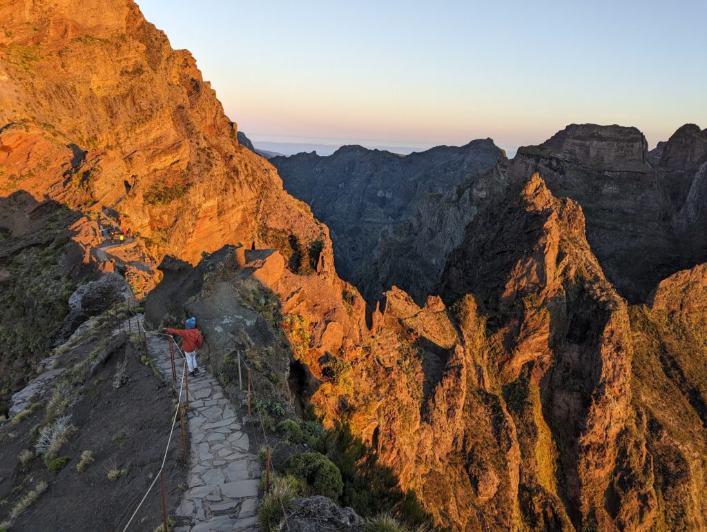 A young boy walking along a stone path surrounded by jagged mountains in Madeira, Portugal