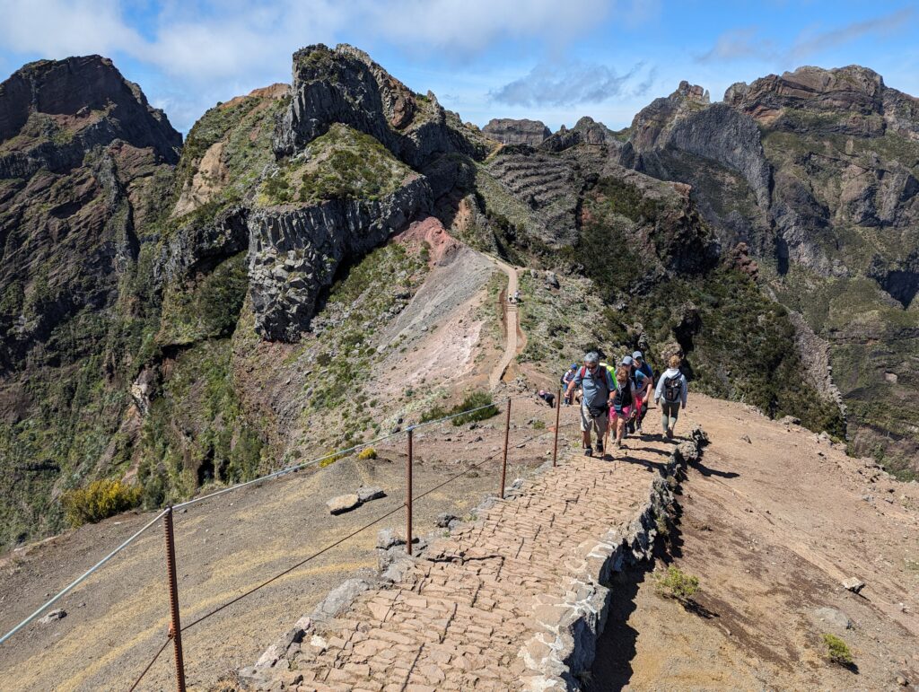 A group walking up a stone staircase on a wide path in the mountains