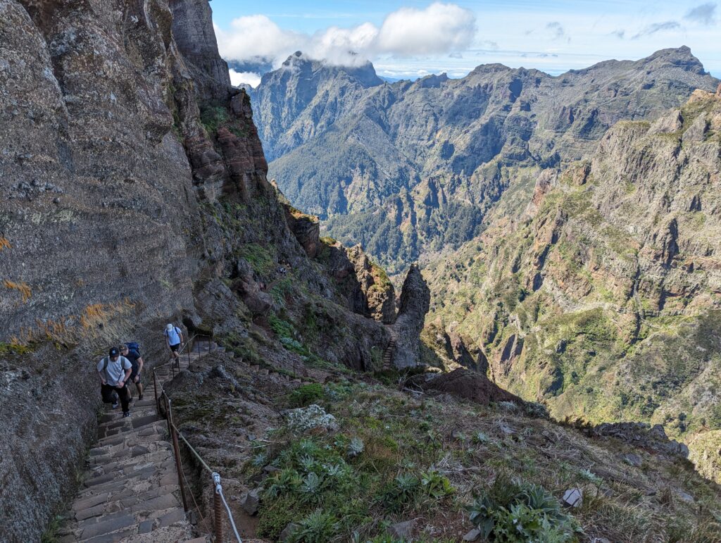 People coming up a stone staircase with  mountains in the background