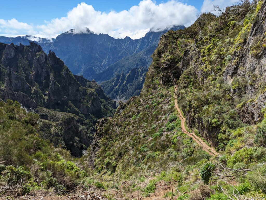 A dirt trail leading through mountain scenery on a cloudy day