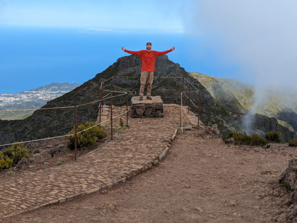 A man standing on a small stone platform atop Pico Ruivo