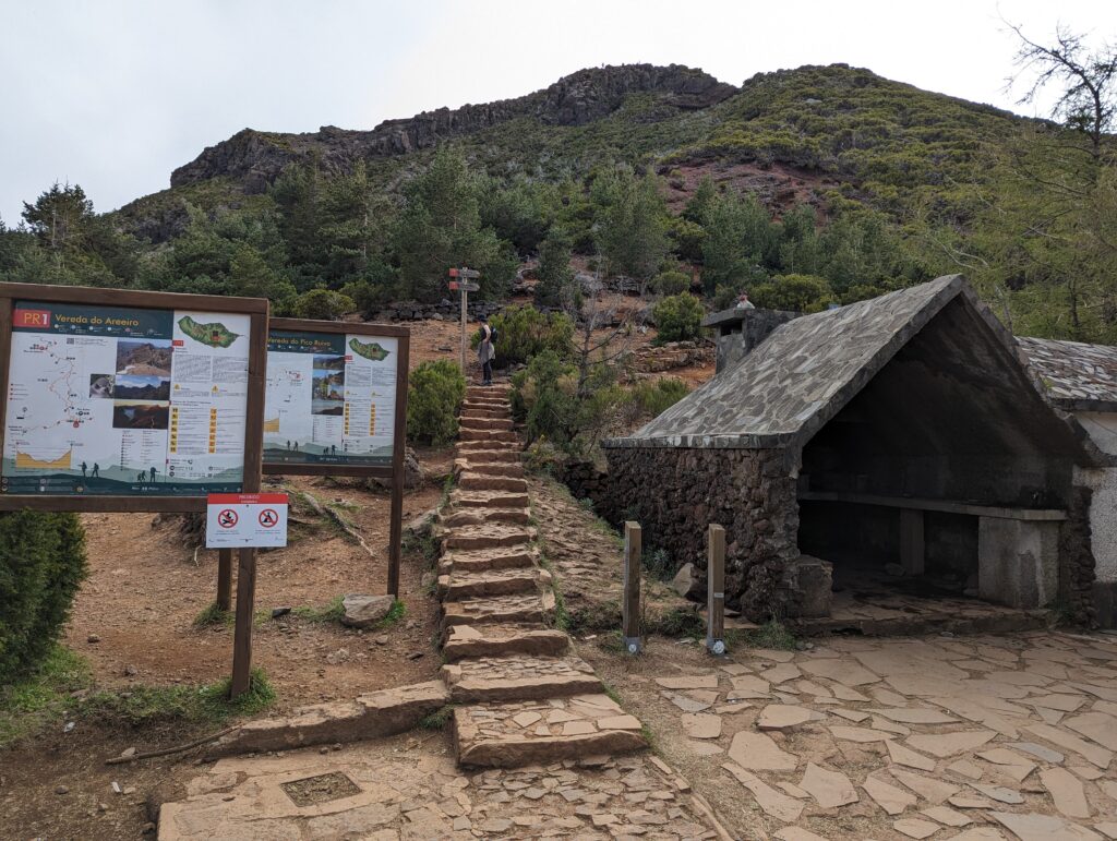 A stone staircase surrounded by hiking trail signs and a stone shelter