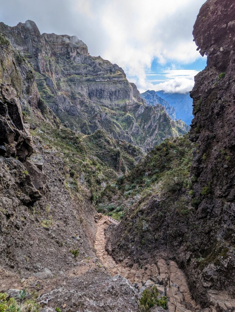 A trail leading through a narrow rock canyon with open mountains further out