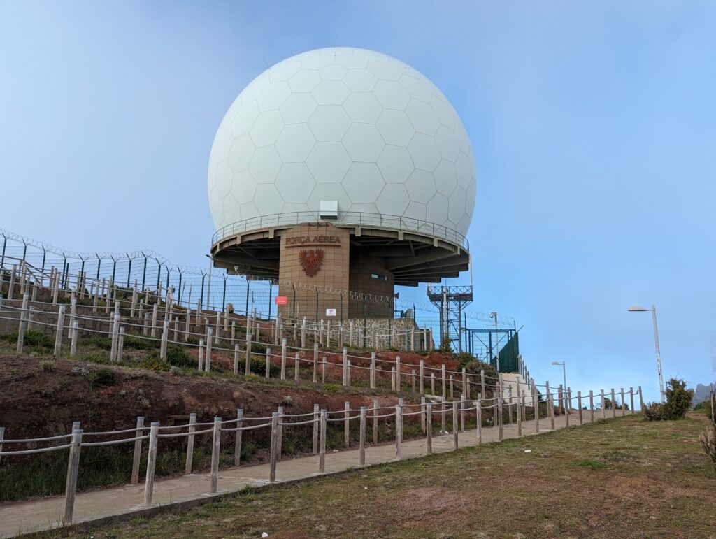 A large white radar station with a blue sky background