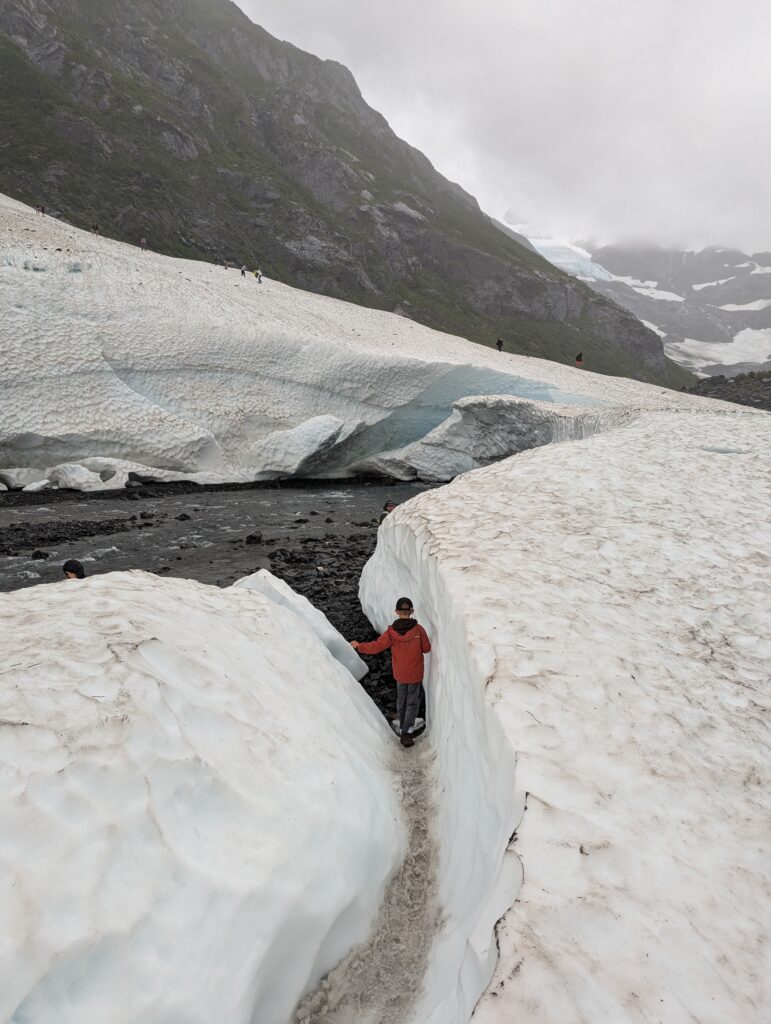 A young boy walking in a crevice of snow at Byron Glacier in Alaska