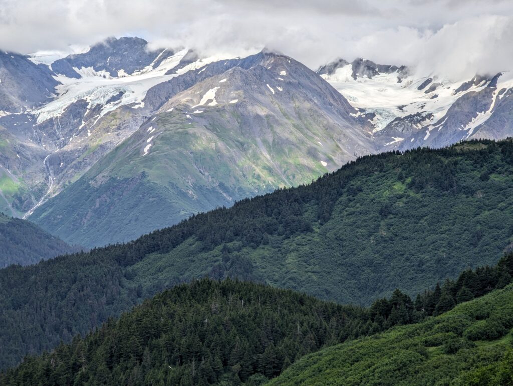 A rounded mountain peak with glaciers on either side on a cloudy day