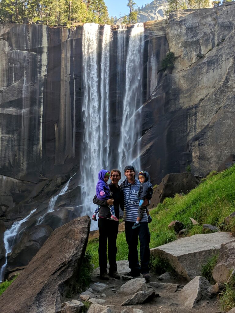 A family standing in front of a waterfall in Yosemite National Park