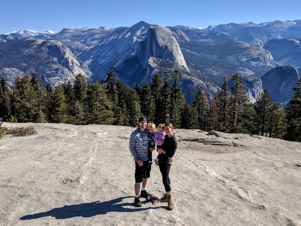 A family standing on Sentinel Dome with Half Dome in the background